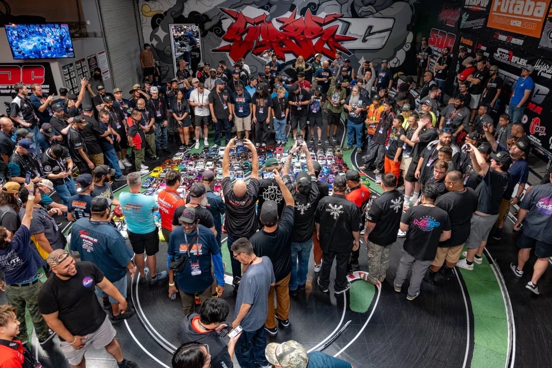 Drivers and spectators crowd around a grid of RC drift cars on the track at Super-G during the 2025 Super Drift Competition Worlds